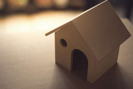 Concept of home purchase mortgage. Wooden toy house on cardboard, vintage image processed.の写真素材