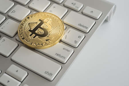 Golden Bitcoin Cryptocurrency gold coin on computer keyboard and return button.の写真素材