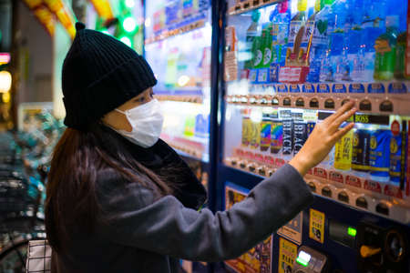 Tokyo, Japan - February 16, 2017 : Woman selecting drinks from vending machine in Japan Downtown.のeditorial素材