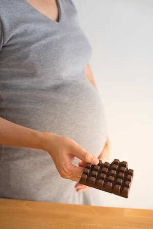 Pregnant woman with chocolate bar.