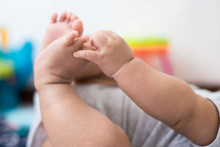 Baby touching or catching feet closed upの写真素材