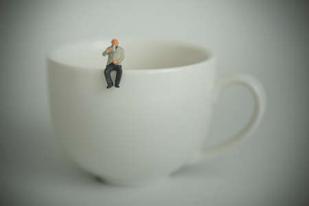 Elderly businessman sitting and drinking coffee on a cupの写真素材