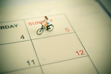 Girl riding bicycle with vintage  weekend calendar background.の写真素材