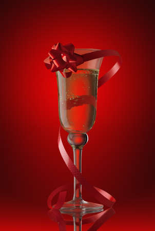 champagne glass with a red tape and a bow on  red backgroundの写真素材