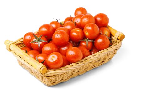 cherry tomatoes in a wattled basket isolated on the whiteの写真素材