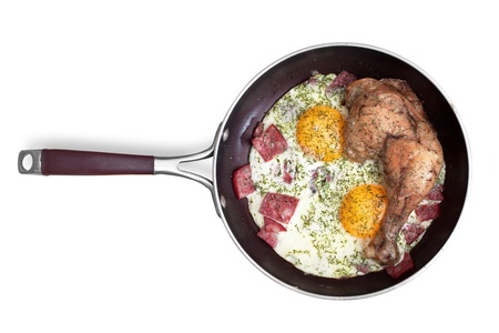 fried eggs with sausage and chicken leg on a frying pan. is isolated on white backgroundの写真素材