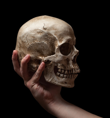 hand holding a skull is isolated on black backgroundの写真素材