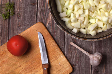 chopped vegetables in a cast iron frying pan on a wooden table. vegetable stew recipeの写真素材