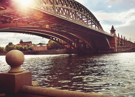 Old iron bridge over the river in the city. bright sunset. Photo in brown red colorsの写真素材