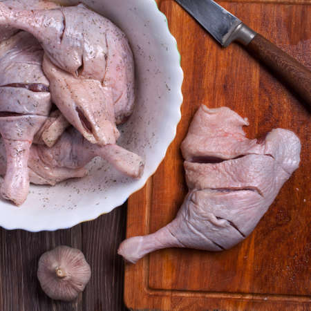 raw duck leg with spices. on the plate. background wooden tableの写真素材