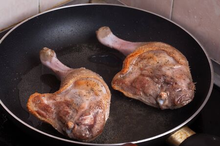 raw duck legs are fried in a pan.の写真素材