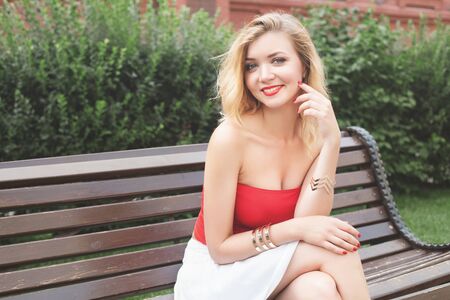 young beautiful girl in a white skirt and a red top. walking in the park and cityの写真素材
