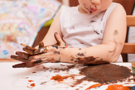 girl sitting at the table and draws paintsの写真素材