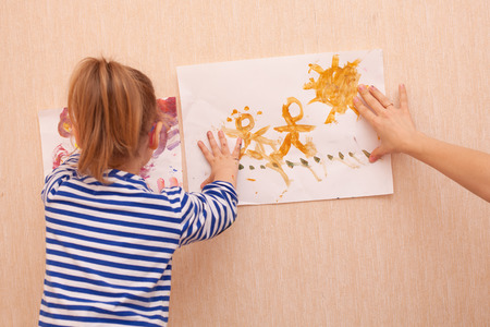 Mom and daughter are trying to hang a picture on the wallの写真素材