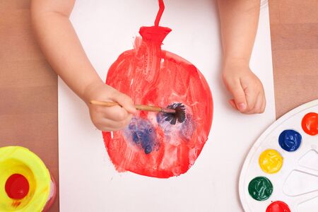view from above. child draws a brush and paints on white paper. balloonの写真素材