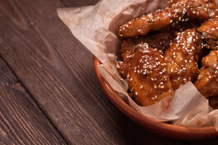 Chicken wings: honey, sesame, ginger. on a wooden table.