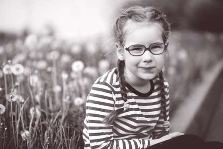 beautiful emotional girl with glasses playing with dandelions. childhood conceptの写真素材