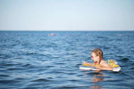 young girl in red glasses and a green bathing suit resting on the sea. childhood and sea airの写真素材