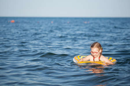 young girl in red glasses and a green bathing suit resting on the sea. childhood and sea airの写真素材