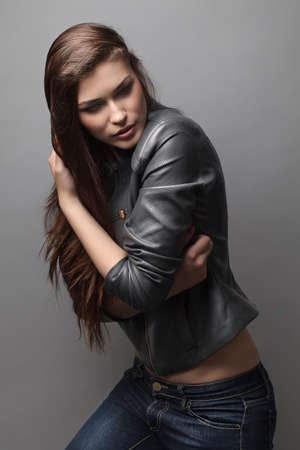 the beautiful girl poses in studio on a gray background. fashion portrait. make-up. long hair.の写真素材