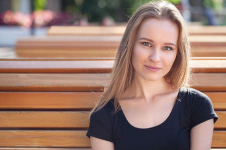 young girl in shorts, sits on a bench. emotional portrait. life styleの写真素材