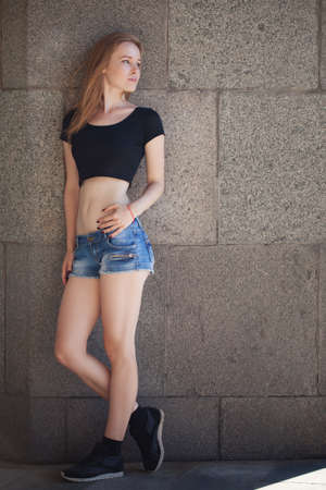 a young girl in shorts and a black topic in the city. bright emotions, style life, sunny dayの写真素材
