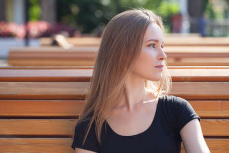 young girl in shorts, sits on a bench. emotional portrait. life styleの写真素材