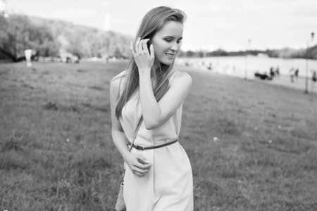 portrait of a young blonde girl in a blue dress. trees in flowers.の写真素材
