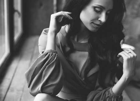 young beautiful girl is sitting by the window. romantic image in a dress.の写真素材