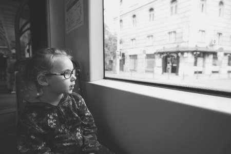 a young girl is riding in a tram and looks with curiosity on the sidesの写真素材