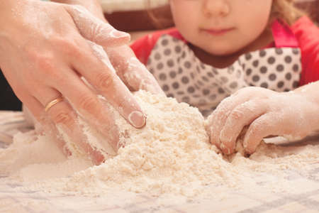 Homemade cookies with raisins on the table. Daughter helps her mother cook.の写真素材