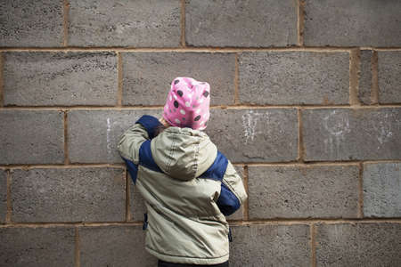 Little girl draws on a gray brick wall