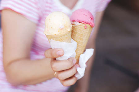a woman in a striped T-shirt is eating ice cream in hot weather