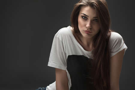 the beautiful girl poses in studio on a gray background. fashion portrait. make-up. long hair.
