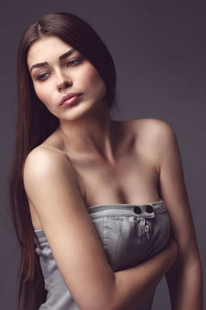 The beautiful girl poses in studio on a gray background. Fashion portrait. Make-up. Long hair.tinted photoの写真素材