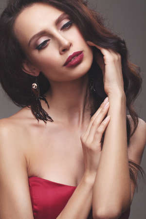 Young slim girl in a red dress. luxury fashion in the studioの写真素材