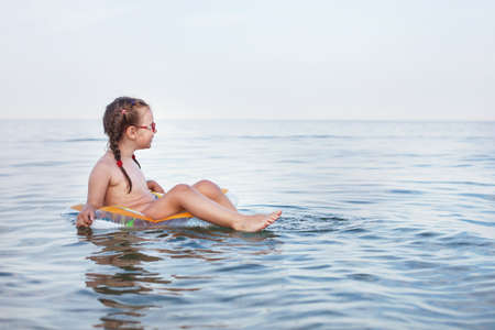 young beautiful girl swims on a rubber ring on the seaの写真素材