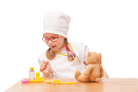 young girl with glasses plays in the doctor as a mom and treats toysの写真素材
