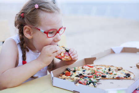 young girl eat delicious italian pizza from cardboard boxの写真素材