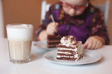 the child is eating a sweet puff cake in a cafe. soft blurry backgroundの写真素材