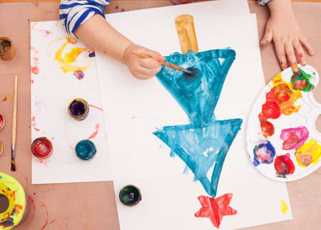 view from above. child draws a brush and paints on white paperの写真素材
