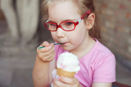 girl in pink dress eating ice cream in hot weather