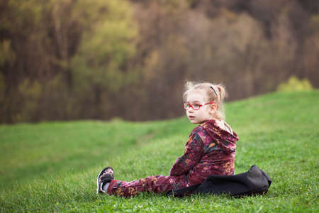 girl sitting on the grass on the background of trees. big green hillの写真素材