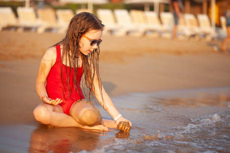 young girl in glasses plays on the sand beachの写真素材