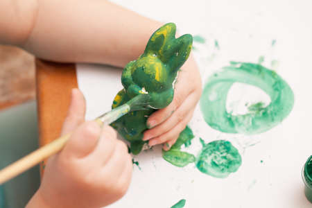 kid paints the figure of a rabbit with green paintの写真素材