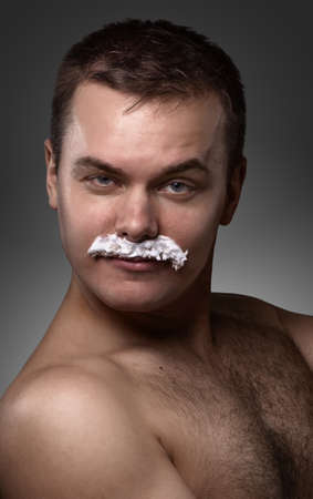 portrait of the young  man. without clothes, with mustaches from the foam, flirting a lookの写真素材