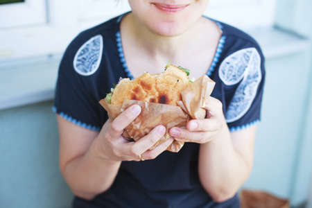 The girl is holding a big hamburger. Soft blurry background. life style