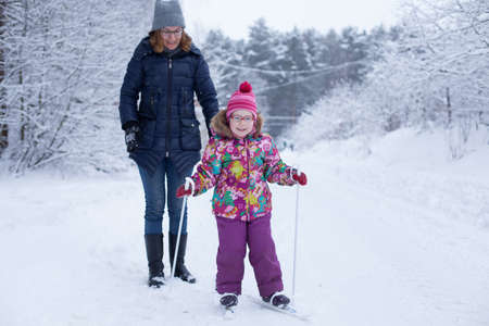 Mom and daughter are learning to ski in forestの写真素材