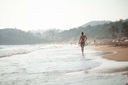 beautiful girl in a swimsuit walks along the beach, the concept of a healthy lifestyle and rest in silenceの写真素材