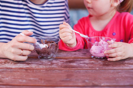 mother and daughter eating tasty ice cream in a cafeの写真素材